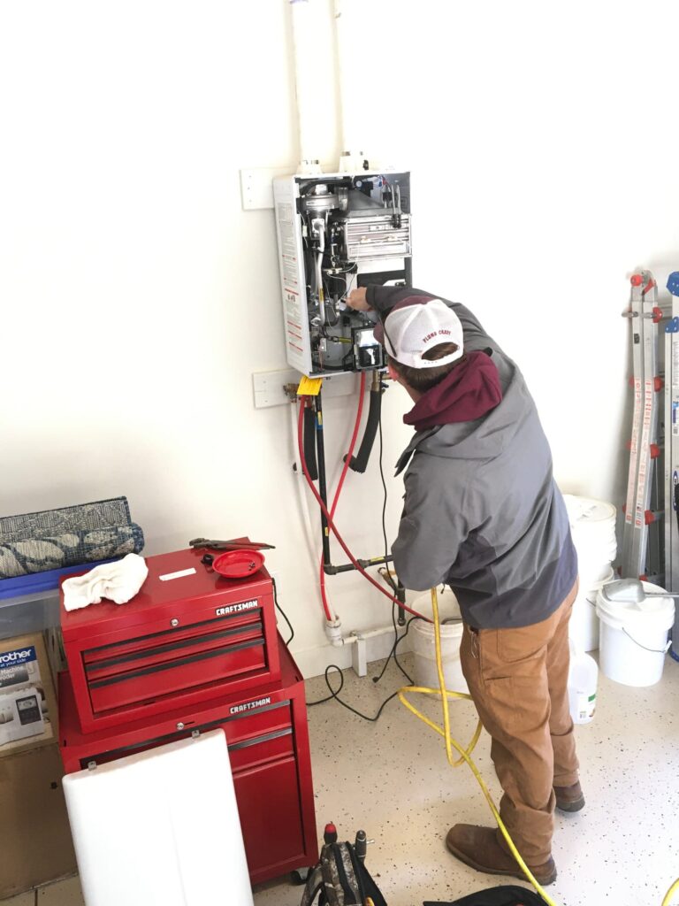 water heater plumber with his hand against a tankless water heater