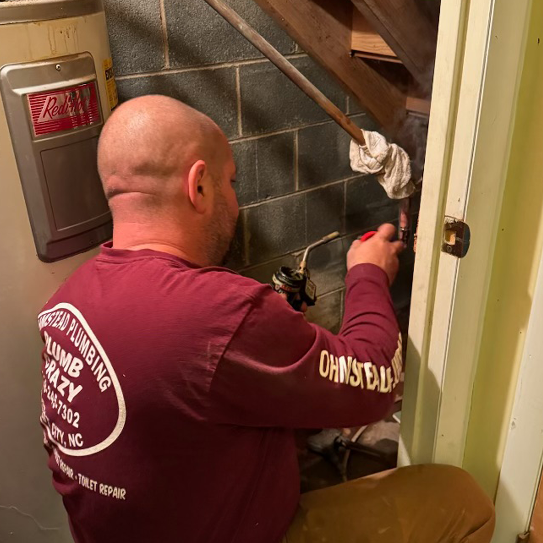 plumber-fixing-a-broken-pipe rozen pipe damage signs including bulged copper pipe section and mineral deposits at fitting from winter freeze