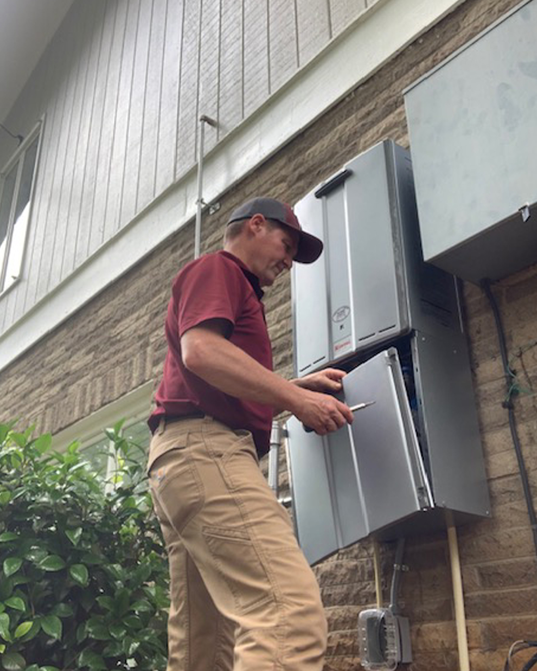 Ohmstead Plumbing technician servicing a Rheem Performance water heater in a local NC home